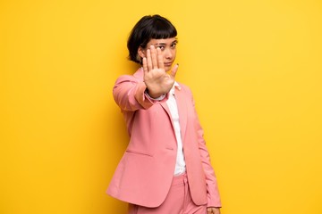 Modern woman with pink business suit making stop gesture denying a situation that thinks wrong