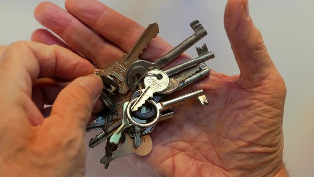 a man holds a bunch of old keys in his hand and looks for the right one