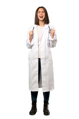 A full-length shot of a Young doctor woman shouting to the front with mouth wide open over isolated white background