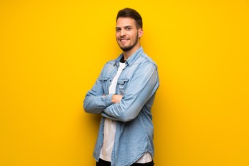 Fototapeta premium Handsome man over yellow wall with arms crossed and looking forward