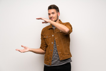 Handsome man over white wall holding copyspace to insert an ad