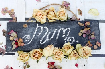 Mum handwritten on a slate surrounded by dried roses 