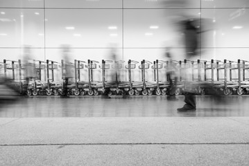 Blurred image of people walking in the airport with a airport trolley as the background.