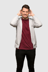 Man with sweatshirt frustrated and takes hands on head over grey background