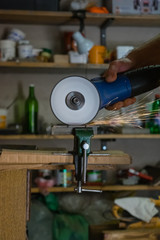 Men cuts a small metal sheet with an electric grinder