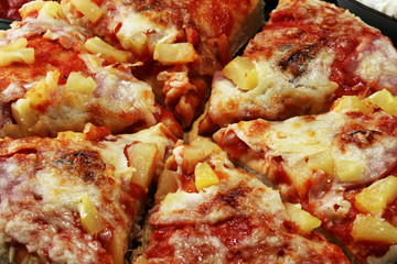 Delicious pizza with pineapple, ham slice, bacon slice, mozzarella cheese, pizza sauce on rustic background for fast food and ready to eat concept