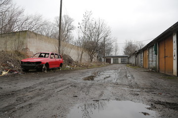 Old, neglected, ruined garages. Muddy, holey, uneven road with puddles. Winter, autumn landscape in the city. Wrocław, Wroclaw, Breslau. Lower Silesia, Dolny Śląsk. Polska, Poland, Polen