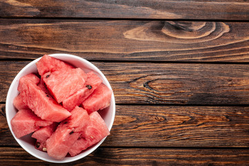 slices of fresh watermelon on plate over wood background,