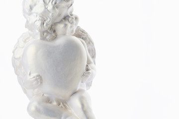 Cherub statue isolated on white background. Angel holds the heart. Love