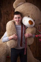 Cheerful guy took a huge Teddy bear on his back