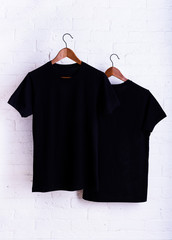Black blank t-shirt, clothes hanging, white background.