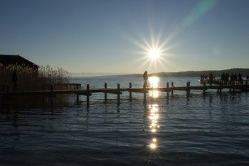 Obraz premium Menschen auf dem Steg am Starnberger See bei Sonnenuntergang