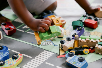 child playing with wooden toy cars on a carpet with streets