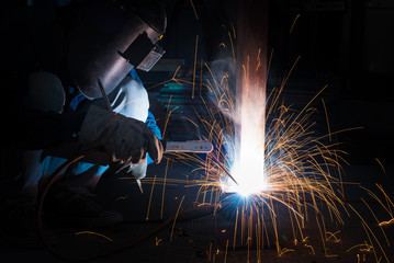Welding skills training of welder with protective mask and welding steel metal part.