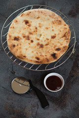 Metal cooling rack with ossetian pie, vertical shot on a grey asphalt background