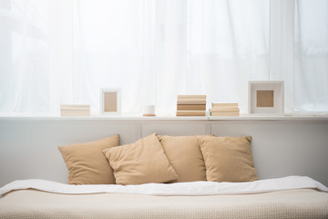 bedroom with brown pillows on bed, books, coffee cup and photo frames