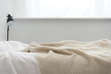 selective focus of empty bed with blanket and lamp