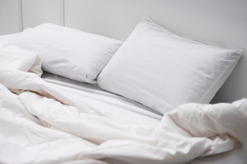 empty bed with white pillows and blanket