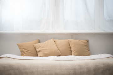 bedroom with brown pillows and white blanket on empty bed