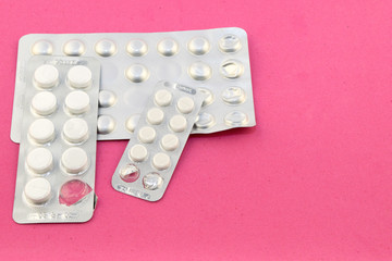 three packs of pills on a pink velvet background