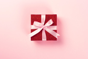 Red gift box with pink ribbon on pink background. Christmas, Valentine's day or birthday concept....