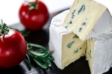 Assorted cheeses on wooden board. Camembert, cheese with blue mildew, mozzarella with tomatoes