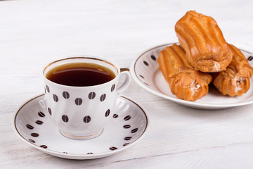 Profiteroles with cream on the table with a Cup of coffee