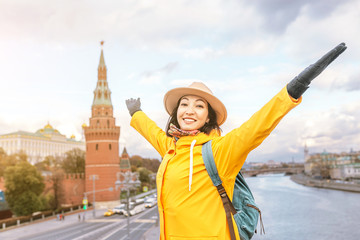 Happy asian woman tourist on the background of the Kremlin wall tower from the Moscow river embankment. Travel in Russia concept