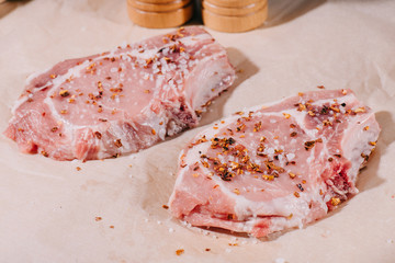 close up of raw fresh steaks with seasoning on paper