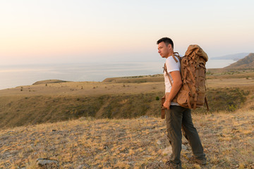 Tourist puts on his backpack in the middle of the steppe