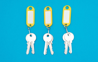 Three keys pair on yellow keychains blue background and copyspace
