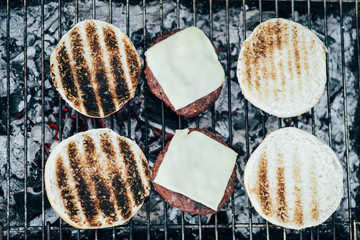 top view of delicious fresh burgers ingredients grilling on bbq grid