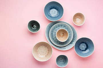 Beautiful blue, grey, beige dinnerware, plates bowls on pink table, top view, selective focus
