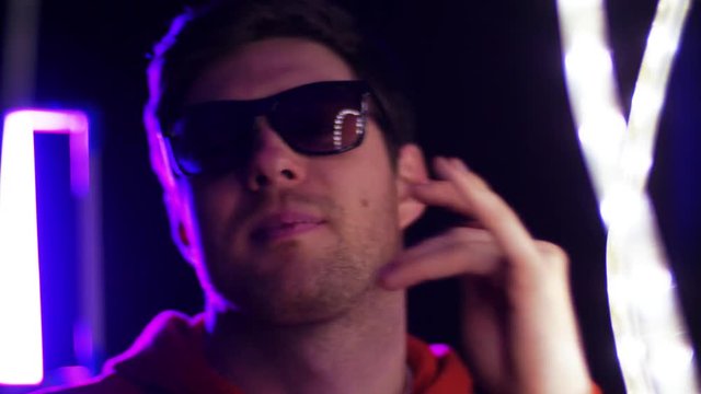 leisure, clubbing and nightlife concept - portrait of smiling young man in sunglasses dancing over ultra violet neon lights in dark room of night club