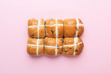 Six hot cross buns, traditional British Easter food on pink background, top view, selective focus