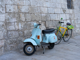 Old scooter and bike on the stone wall background