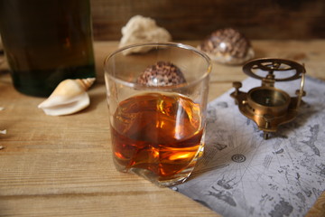 glass of whiskey with a compass and shells on a wooden rustic table with copy space for text