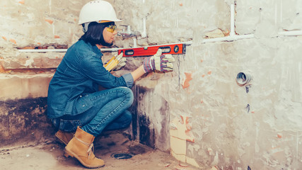 Female construction worker using leveling tool