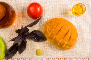 national Adyghe cheese homemade on a woven cloth, with Basil, tomato, sesame oil, chili pepper, on a wooden table