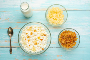 Cottage cheese with raisins and pineapple zucchini, with milk in a bowl on a blue wooden table. Diet, tasty and healthy food