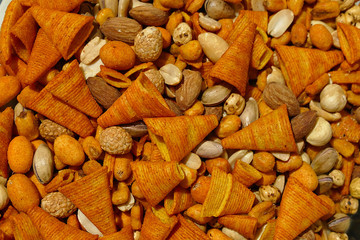 a bowl full of nuts, peanuts, corn chips etc ...