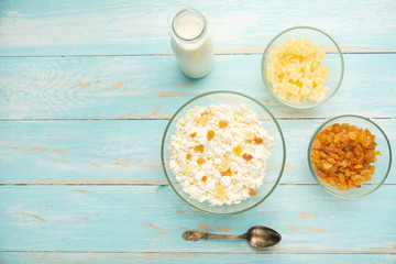 Cottage cheese with raisins and pineapple zucchini, with milk in a bowl on a blue wooden table. Diet, tasty and healthy food. Banner