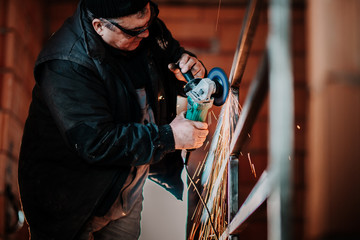 portrait of industrial worker using angle grinder on construction site