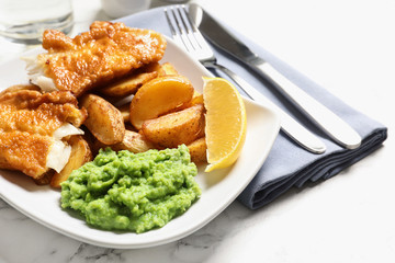 Plate with British traditional fish and potato chips on marble table