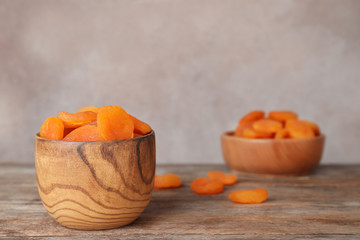 Bowl with apricots on wooden table, space for text. Dried fruit as healthy food