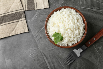Bowl of boiled rice served on grey table, top view with space for text