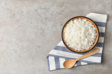 Bowl of boiled rice and spoon on grey background, top view with space for text