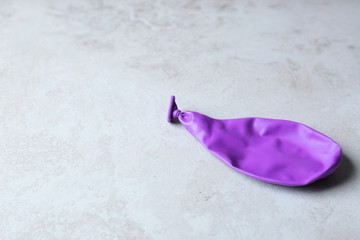 Purple deflated balloon on grey background, space for text