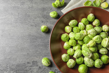plate of fresh Brussels sprouts on grey background, top view with space for text