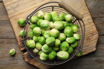 Metal basket with fresh Brussels sprouts on wooden background, top view